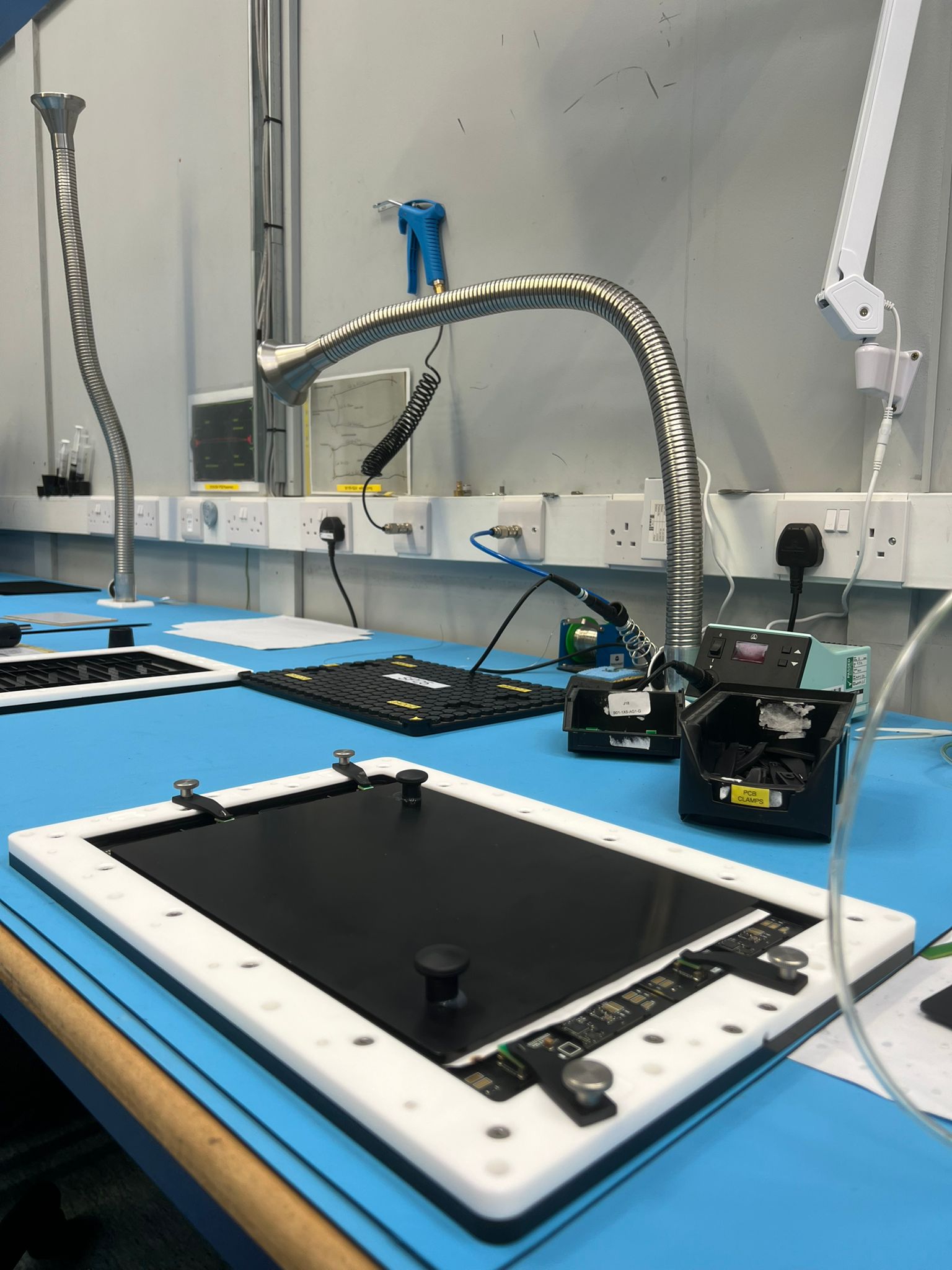 Dedicated motorsport electronics assembly workstation at MPE Electronics with local fume extraction units and tooling for safe, precise potting operations.
