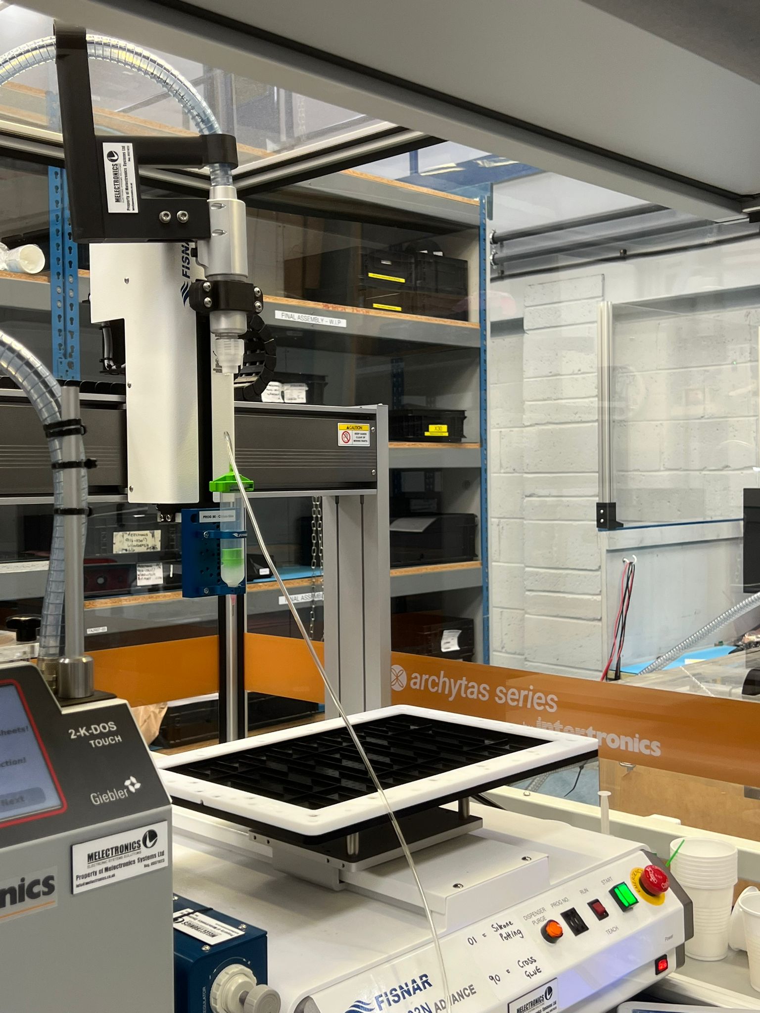 Robotic potting machine applying encapsulation compound to motorsport display units at MPE Electronics, improving precision and repeatability in box build assembly.